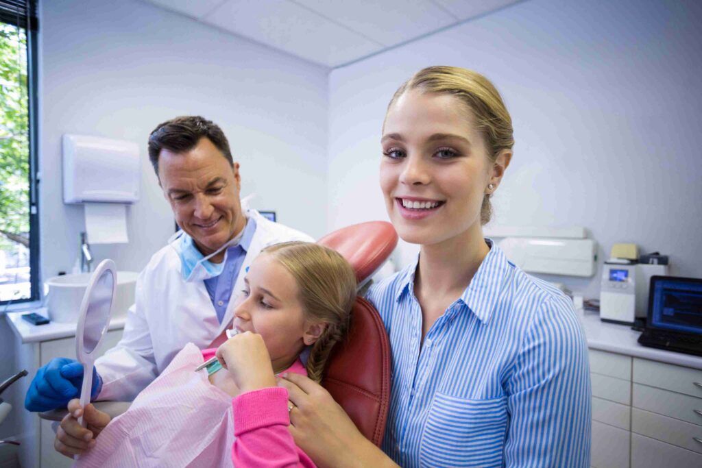 Child and parent smiling during a dental visit.