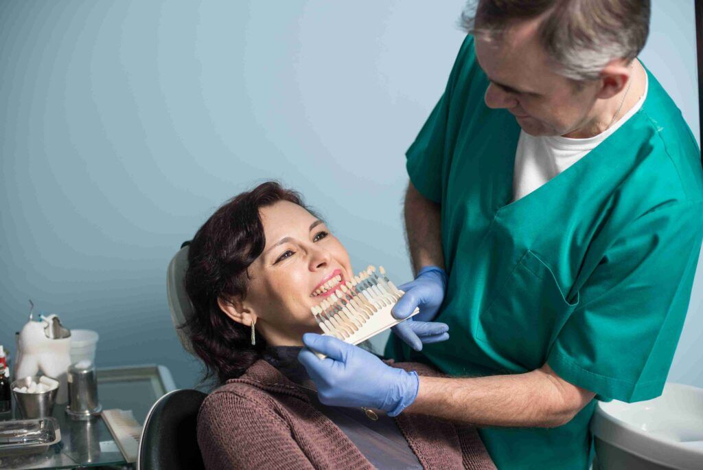 Dentist showing tooth shade options to a smiling patient.