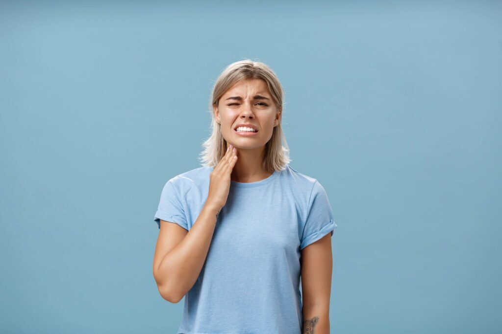 Woman holding her jaw in pain.